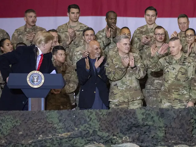 The image shows President Donald Trump speaking at a podium in front of a group of soldiers, with a...