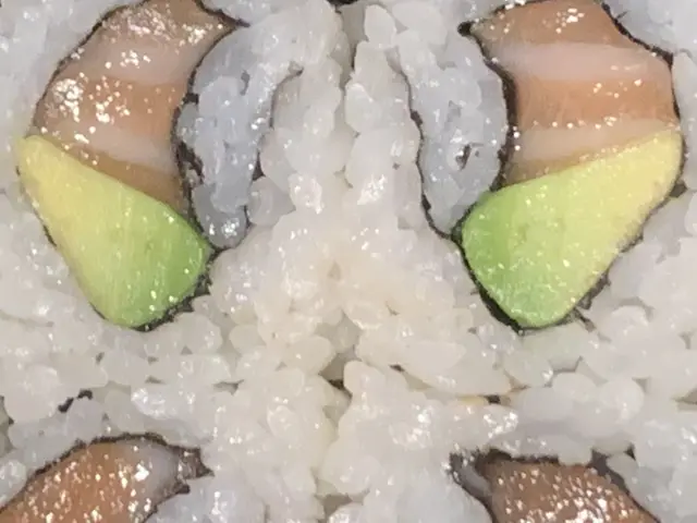 The image shows a close up of a plate of sushi on a table. The plate is filled with a variety of...