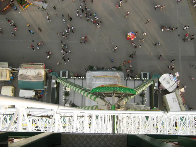 The image shows an aerial view of a carnival ride from the top of a building. We can see a group of...