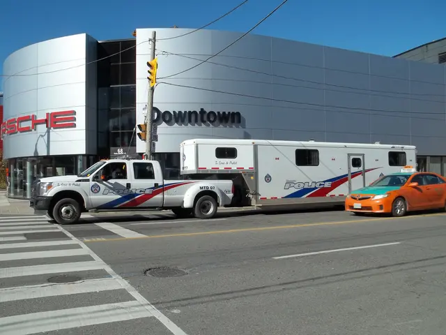 The image shows a police truck parked in front of a building with text on it. There is a traffic...