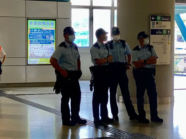 The image shows a group of police officers wearing masks standing in front of a building with glass...