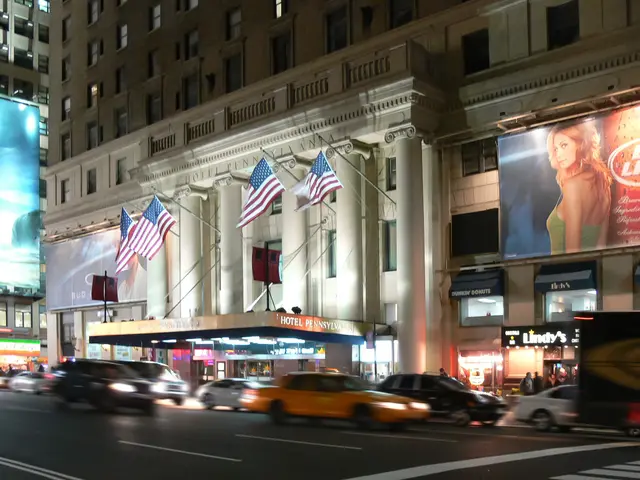 The image shows a bustling city street at night with cars and trucks driving down it. In the...