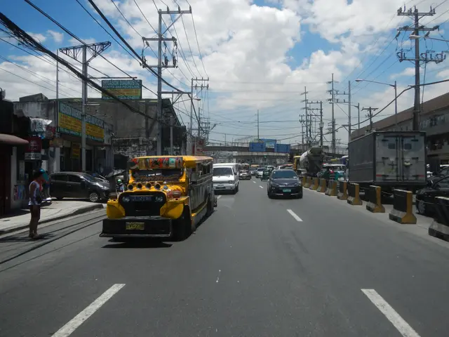 The image shows a yellow school bus driving down a street lined with tall buildings on either side....
