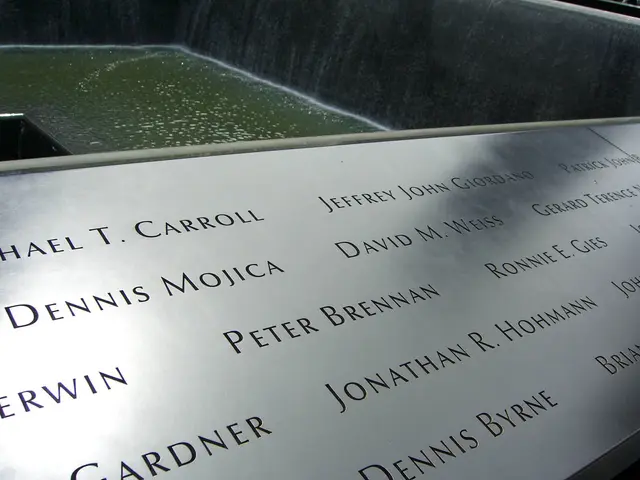 The image shows the 9/11 Memorial in New York City, with a name board in the foreground and a...