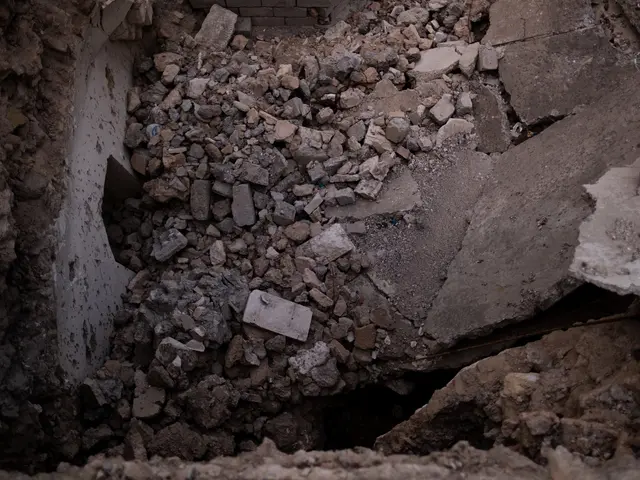 The image shows a collapsed building with a large hole in the ground, surrounded by stones and...