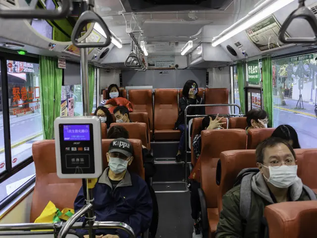 The image shows a group of people wearing face masks riding on a bus. The bus is filled with...