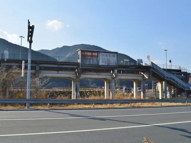 The image shows a highway with a bridge over it, a traffic light on the side of the road, railings,...