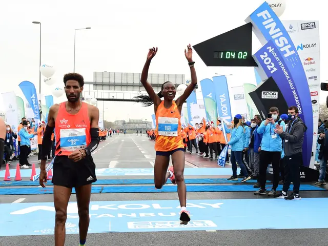 The image shows a man and woman crossing the finish line of a marathon, surrounded by a group of...