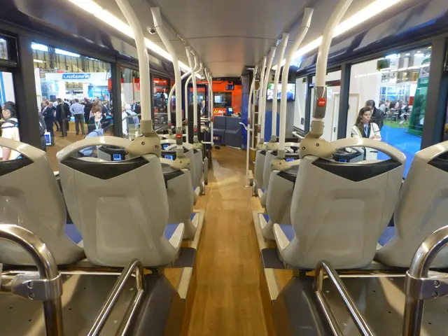 The image shows the interior of a train with many seats, rods, lights, and glass doors. There are...