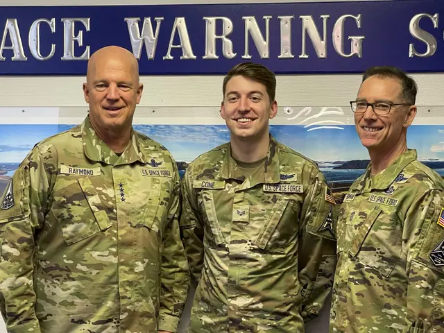 The image shows three men in military uniforms standing next to each other, smiling, with a board...