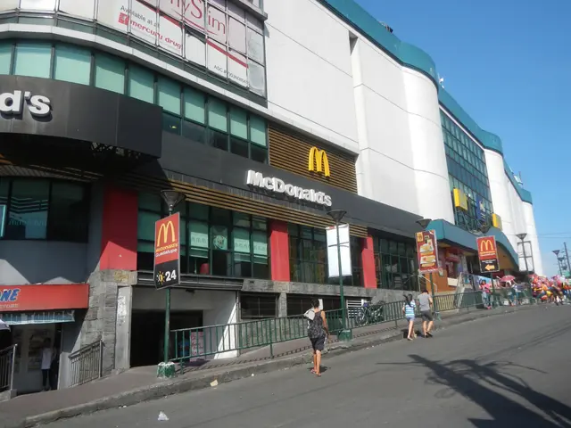 The image shows a McDonald's restaurant on the corner of a street, with a group of people walking...