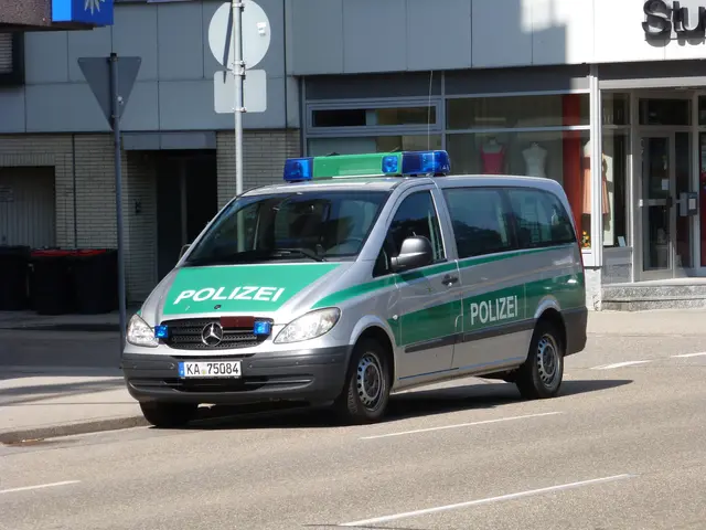 The image shows a police van parked on the side of the road in front of a building with glass doors...