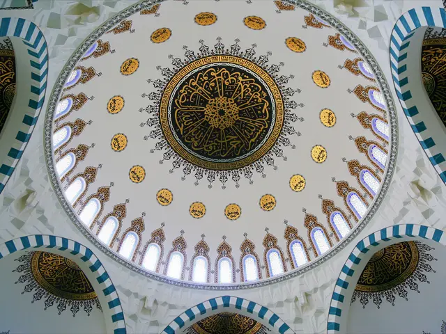 The image shows the interior of a mosque with a dome on top of it. The walls are decorated with...