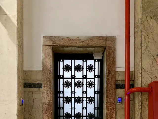 The image shows an elevator in a building with a black and white checkered floor, a door, a red...
