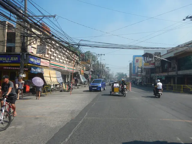 The image shows a city street filled with lots of people riding bicycles and cars, as well as...