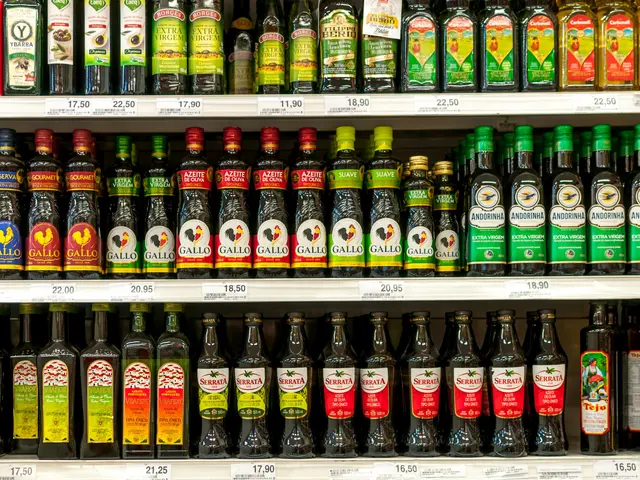 The image shows a store shelf filled with lots of different types of olive oil, each with its own...