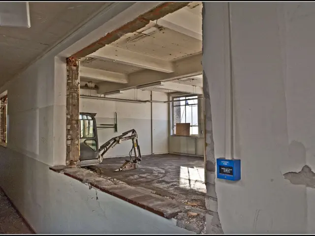 The image shows an excavator in the middle of a room with a broken window, surrounded by walls,...