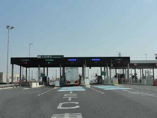 The image shows a toll booth on the side of a road with a truck parked in front of it. The road is...