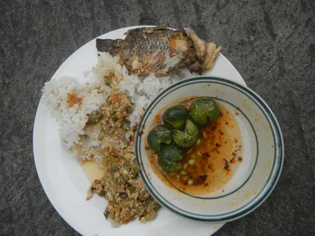The image shows a white plate topped with a generous portion of rice and a fish, accompanied by a...