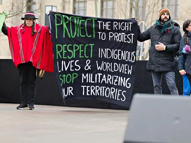 The image shows a group of people standing on the ground, holding a banner that reads "Protect the...