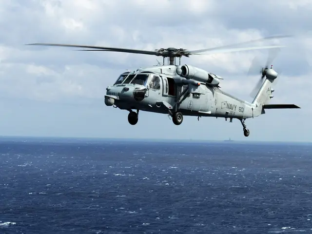 The image shows a helicopter flying over the ocean on a cloudy day, with the water below and the...