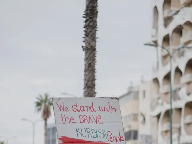 The image shows a group of people walking down a street, holding a sign that reads "We Stand with...