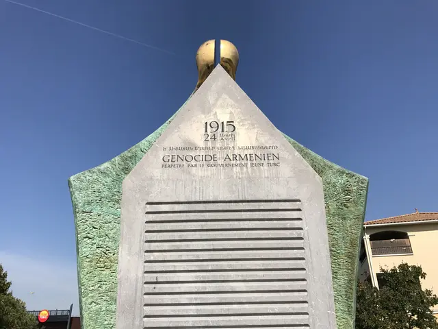 The image shows a monument in the middle of a park with a clock on top of it, surrounded by trees...