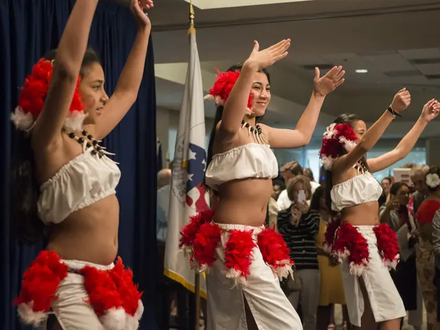 The image shows a group of young women in white and red outfits dancing in front of a crowd of...