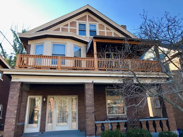 The image shows a large house with a lot of windows, doors, railings, pillars and a roof,...
