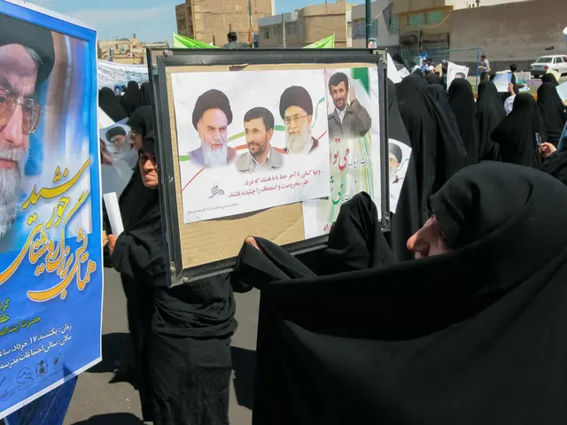 The image shows a group of women in black abayas holding up posters with pictures of Ayatollah Ali...