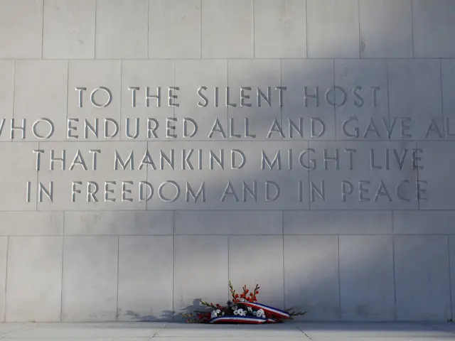 The image shows a memorial wall with the words "To the Silent Host Who Endured All and Gave All...