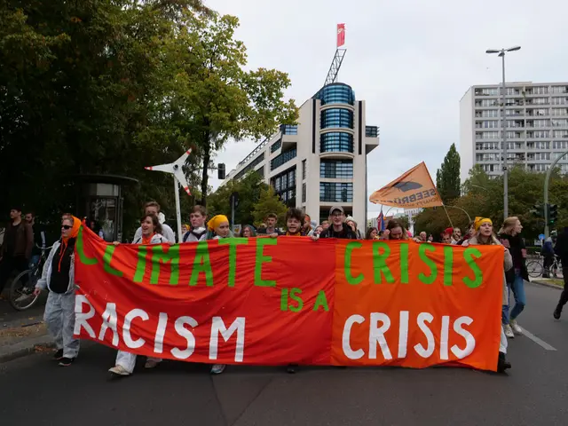 The image shows a group of people walking down a street, holding a banner that reads "Climate...