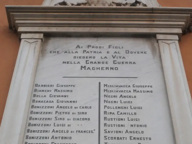 The image shows a monument in front of a building with a plaque on it. The plaque is made of stone...