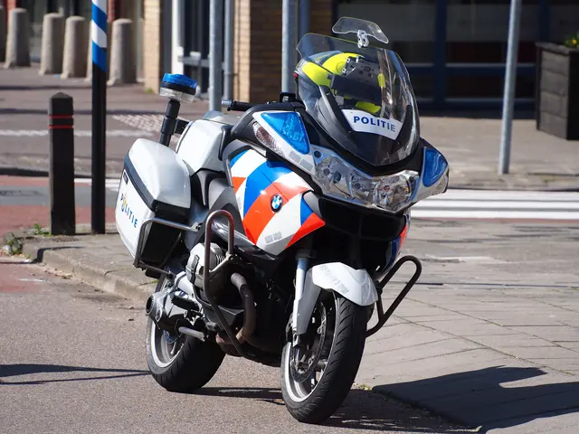 The image shows a police motorcycle parked on the side of the road, with a helmet on the bike. In...