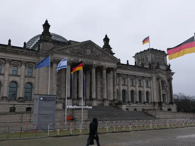 The image shows a person walking in front of the Reichstag building in Berlin, Germany. The...