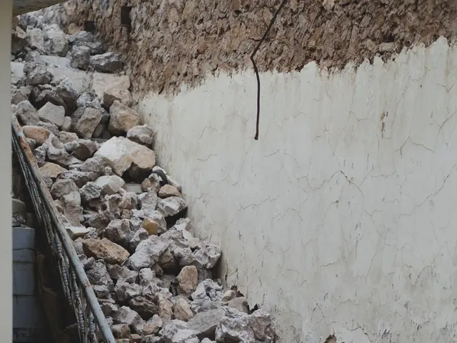 The image shows a pile of rubble next to a building with a wall on the right side and a railing on...