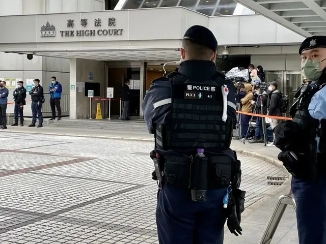 The image shows two police officers standing in front of a building at Hong Kong International...