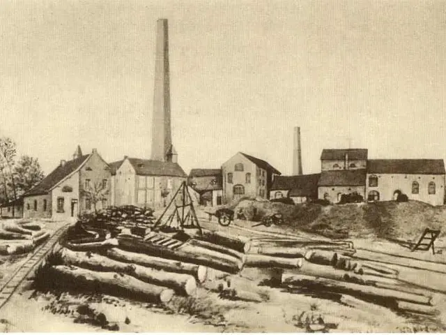 The image shows an old black and white photo of a factory with a pile of logs in front of it. The...
