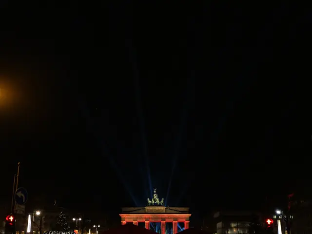 The image shows the Brandenburg Gate in Berlin at night, illuminated by street lights and...