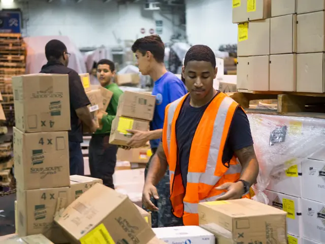 The image shows a group of men in orange vests and safety vests loading boxes into a warehouse....