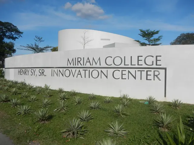 The image shows the Miriam College Innovation Center, with a wall featuring text on it, surrounded...