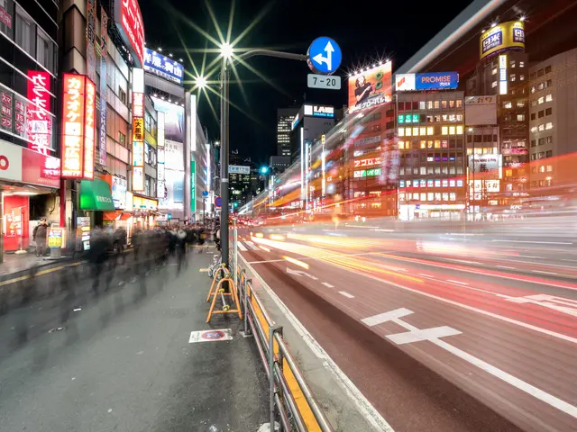 The image shows a bustling city street at night with a lot of traffic on it. We can see a group of...