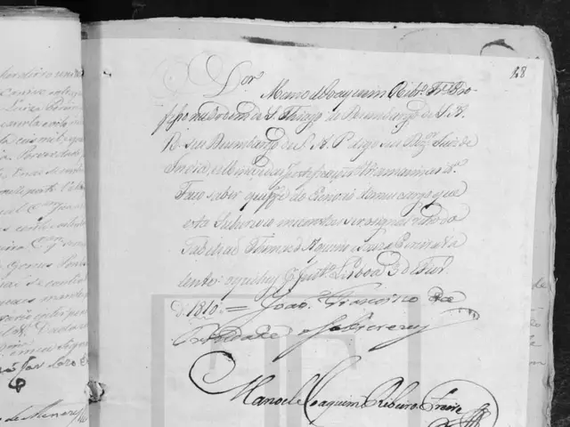 The image shows an open book with handwriting on it in black and white. The text on the book reads...