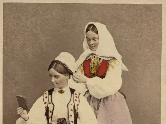 The image shows an old photo of two women in traditional Romanian clothing, one of them sitting and...