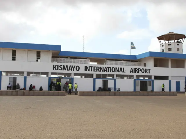 The image shows the Kismayo International Airport in Kenya, with its white and blue building...