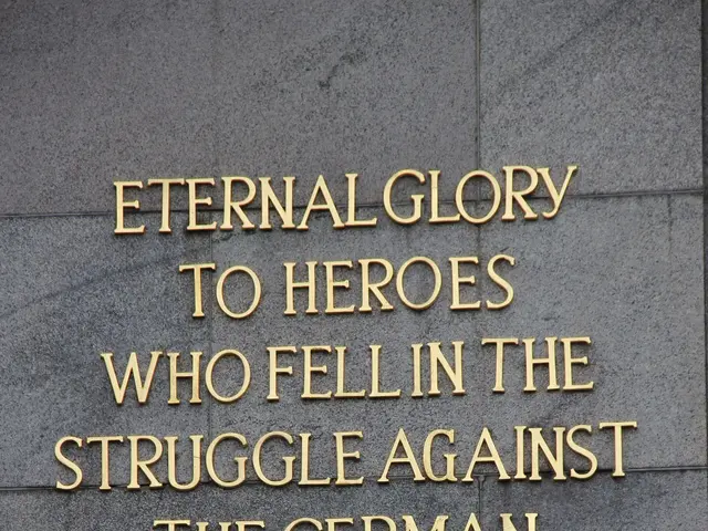 The image shows a stone wall with the text "Eternal Glory to Heroes Who Fell in the Struggle...