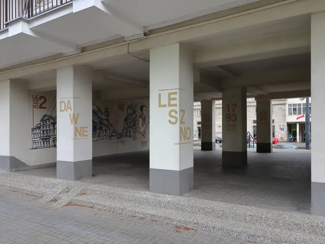 The image shows an empty parking garage with graffiti on the side of it, surrounded by pillars,...