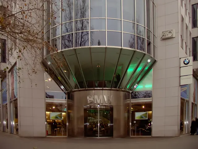 The image shows the BMW headquarters in Frankfurt, Germany. It is a large building with glass walls...