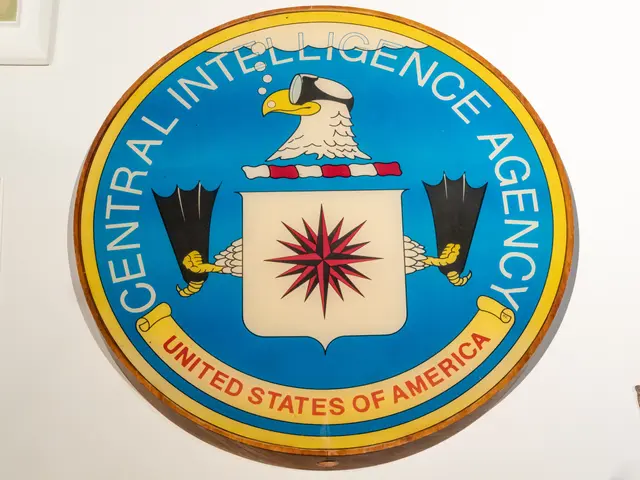 The image shows the CIA logo on a wall in a room, with the text "CIA" written in bold, white...