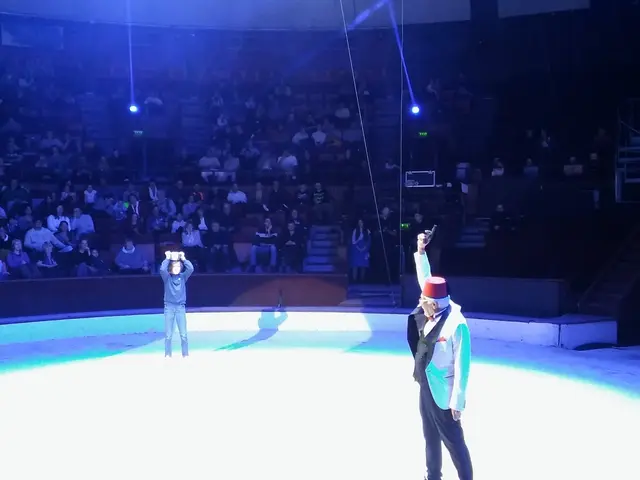 The image shows two men standing on top of an ice rink in front of a crowd. They are both wearing...